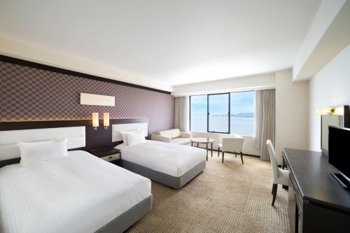 Habitación de hotel con 2 camas y escritorio en Grand Mercure Lake Biwa Resort & Spa, en Nagahama