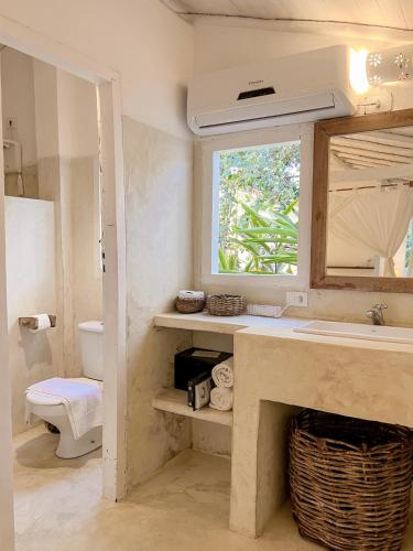 a bathroom with a sink and a toilet and a window at Pousada Lagoa in Caraíva