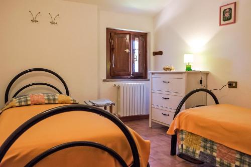 a bedroom with two beds and a dresser and a window at La Casanuova in Laiatico