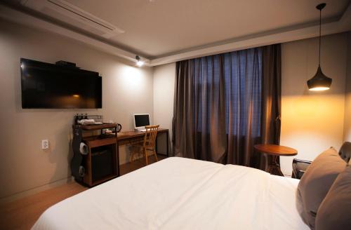 um quarto de hotel com uma cama, uma secretária e uma televisão em Brown Dot Hotel GimhaeEobang em Gimhae