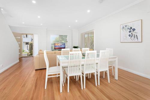 a white dining room with a table and chairs at Sea La Vie in Shellharbour
