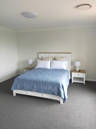 a bedroom with a bed with a blue blanket and two tables at Sea La Vie in Shellharbour