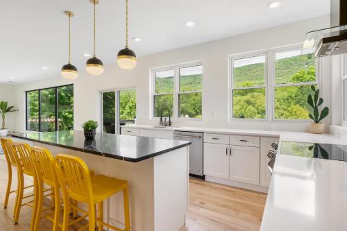 a kitchen with white cabinets and yellow chairs at Malkita Aria Mountainview Retreat in Woodbury