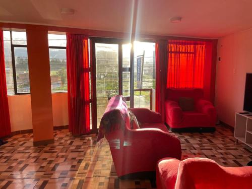 een woonkamer met rode meubels en ramen bij CASA HOSPEDAJE LAS MONTAÑAS in Huancayo