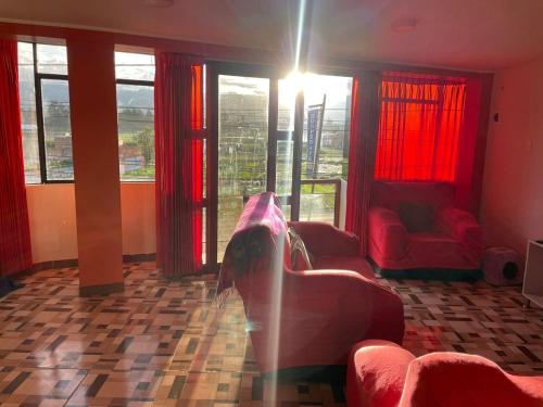 een woonkamer met rode meubels en grote ramen bij CASA HOSPEDAJE LAS MONTAÑAS in Huancayo