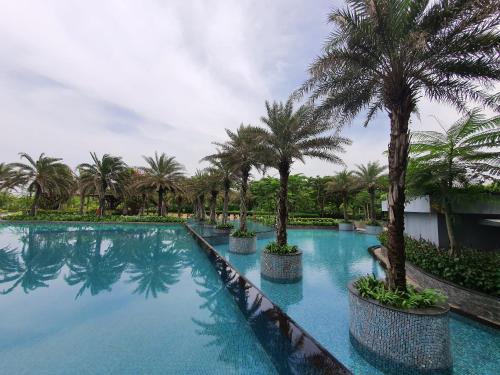 a swimming pool with palm trees in a resort at Luxurious Flat 2BR in Gold Coast PIK Penjaringan in Jakarta