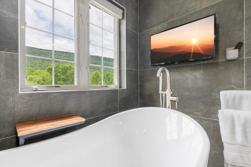 a bathroom with a tub and a tv on the wall at Malkita Aria Mountainview Retreat in Woodbury