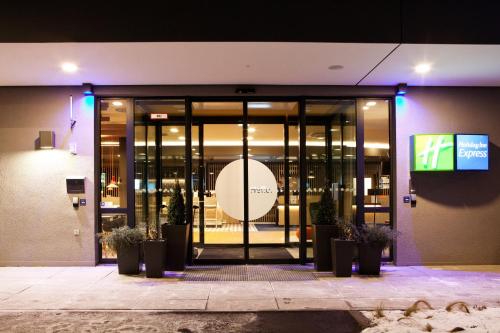 a glass entrance to a building with potted plants at Holiday Inn Express Munich - Olympiapark by IHG in Munich