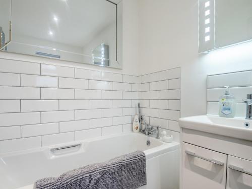 a white bathroom with a tub and a sink at Walcot House Stables in Diss