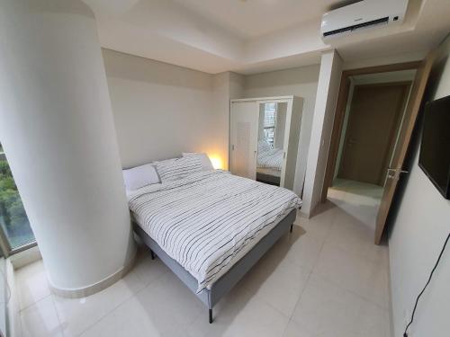 ein kleines Schlafzimmer mit einem Bett in einem Zimmer in der Unterkunft Luxurious Flat 2BR in Gold Coast PIK Penjaringan in Jakarta