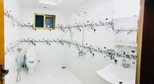 a white bathroom with a toilet and a sink at Grand Taj in Murree