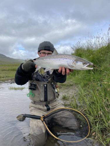 a man in the water holding a fish at Hótel Hvítserkur in Hvammstangi