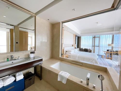 een badkamer met een bad, een bed en een spiegel bij Sheraton Zibo Hotel in Zibo