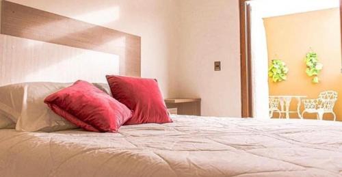 Una cama con dos almohadas rojas encima. en Hotel boutique, en La Serena