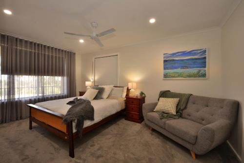 Jacks Kangaroo Island في كنغزكوت: غرفة نوم بسرير واريكة ونافذة