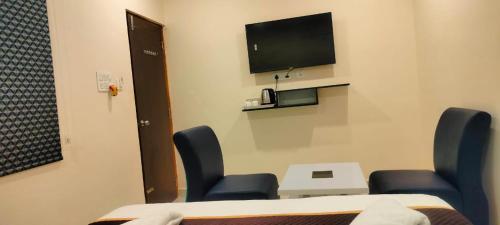 a room with chairs and a tv on a wall at HOTELPEACOCKINN in Visakhapatnam