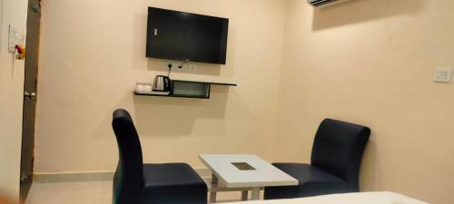 um quarto com duas cadeiras e uma mesa e uma televisão em HOTELPEACOCKINN em Visakhapatnam