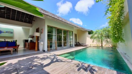 a villa with a swimming pool and a patio at The Decks Bali in Legian