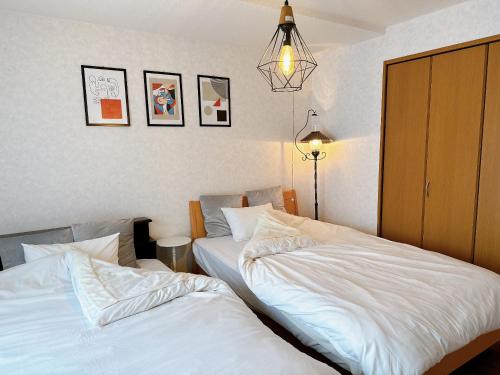 dos camas sentadas una al lado de la otra en un dormitorio en 民宿にしかぐら, en Higashikawa
