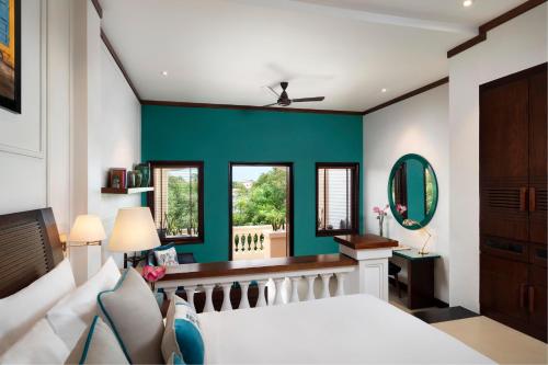 ホイアンにあるアナンタラ ホイアン リゾートの緑の壁のベッドルーム1室(白いベッド1台付)