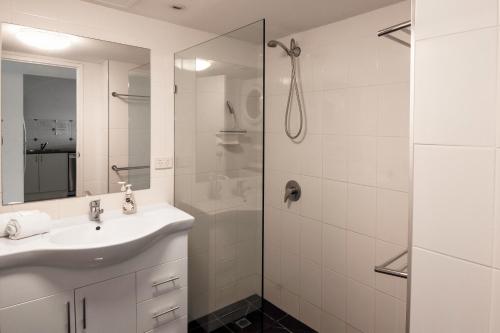 a white bathroom with a sink and a shower at Key Largo Holiday Apartments in Gold Coast