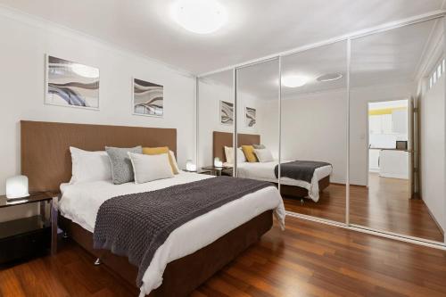 een slaapkamer met een groot bed en een spiegel bij Swan River Applecross Heathcote Park 1BR Villa in Perth