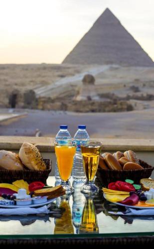 a table with two glasses of drinks and the pyramids at Pyramids hotel in Cairo