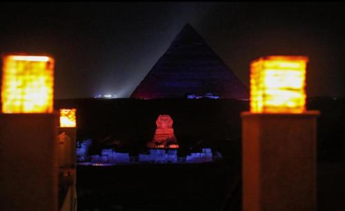 una vista de la esfinge y las pirámides por la noche en Pyramids hotel, en El Cairo