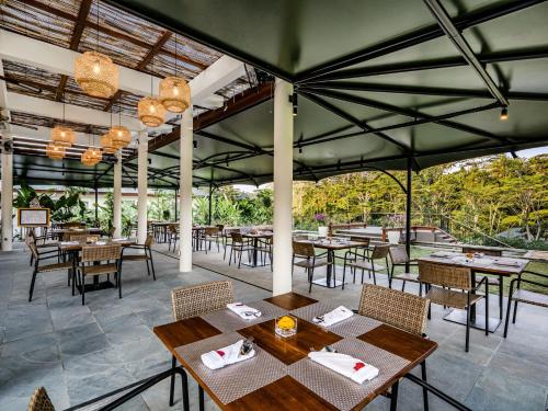 un restaurante al aire libre con mesas, sillas y lámparas de araña en The Pala Ubud by Elite Havens, en Bedahulu