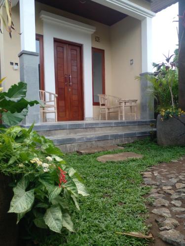 un porche delantero de una casa con puerta roja en Candy home stay en Klungkung
