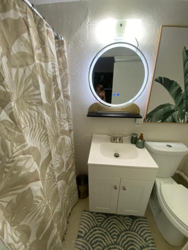 a bathroom with a sink and a mirror and a toilet at Stylish studio near Kuhio Beach in Honolulu