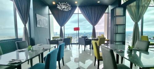 a dining room with tables and chairs and large windows at The Shore Hotel & Residences in Melaka