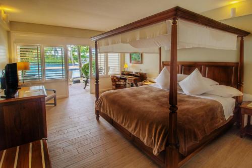 a bedroom with a canopy bed and a desk at Plantation Bay Resort and Spa in Mactan