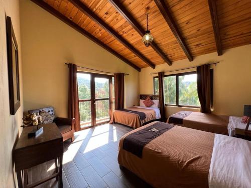 a bedroom with two beds and a couch and windows at Cabaña No. 5 Puerta del Bosque Mazamitla. in Mazamitla