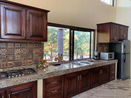 a kitchen with wooden cabinets and a large window at Cabaña No. 5 Puerta del Bosque Mazamitla. in Mazamitla