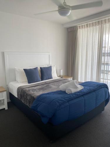 a bedroom with a large blue bed with a window at Cilento Mooloolaba in Mooloolaba