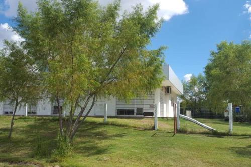 a white house with a tree and a slide at Casa cero stress in Salto