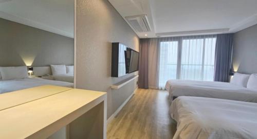 um quarto de hotel com duas camas e uma televisão de ecrã plano em Air City Hotel Corp em Jeju