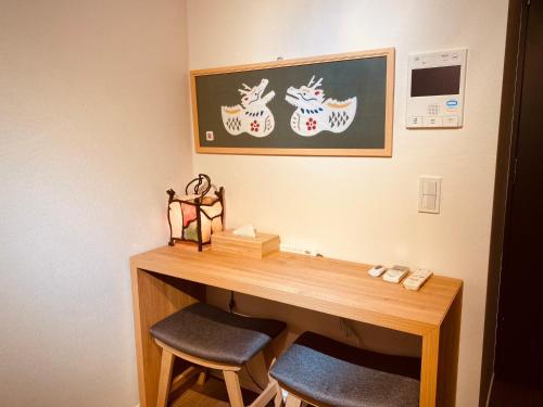 東京にあるSakura Retreat Ryokan- Haneda Gateway-澪のデスク(椅子2脚付)が備わります。壁に絵が描かれています。