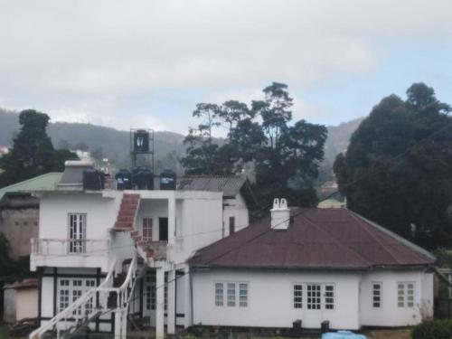 a large white house with a staircase in front at Frosty Heaven Guest House in Nuwara Eliya