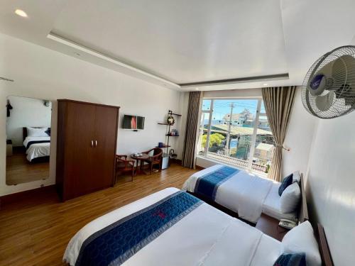 a hotel room with two beds and a window at Cosy Hotel & Apartment Dalat in Da Lat
