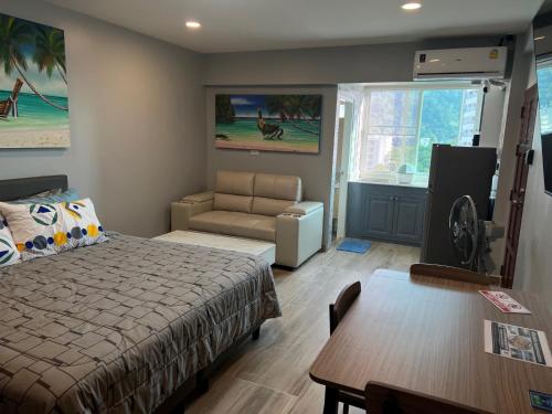 a bedroom with a bed and a living room at Patong Vacation Rentals - 28 SQM Studio Apartments - Located in the Heart of Patong with Kitchen, Private Bathroom, Seating Area, 65" Smart TV with Free WIFI in Patong Beach