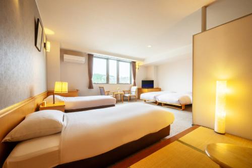 a hotel room with two beds and a desk at Hotel Yutoria Fujisato in Fujisato