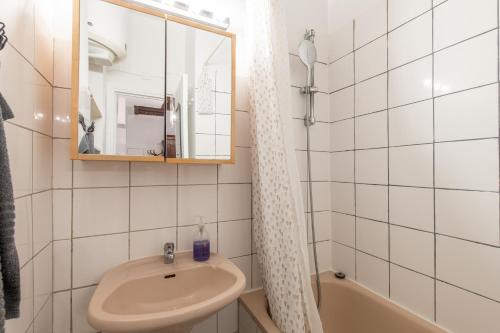 une salle de bain avec un lavabo, un miroir et une baignoire dans l'établissement Geranimus Beauregard: Heart of Paris, à Paris