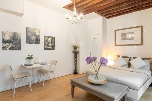 - une chambre avec un lit et une table ornée de fleurs violettes dans l'établissement Geranimus Beauregard: Heart of Paris, à Paris