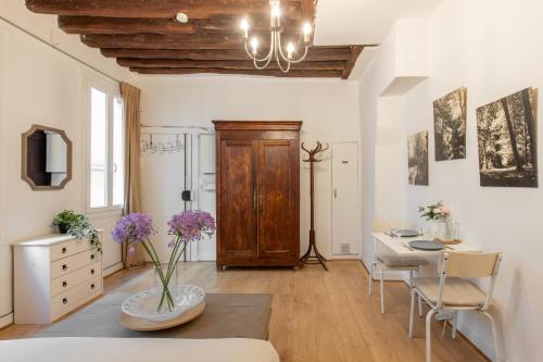 - un salon avec une table et un bureau orné de fleurs violettes dans l'établissement Geranimus Beauregard: Heart of Paris, à Paris