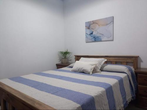 1 dormitorio con 1 cama con manta de rayas azul y blanco en El Molino cabañas en General Juan Madariaga