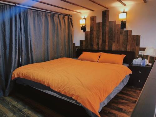 a bedroom with a large bed with an orange comforter at Hills&MING B&B in Shanghai