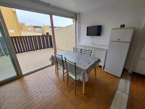 une table et des chaises dans une pièce avec un réfrigérateur dans l'établissement Appartement 2 Pièces avec Grande Terrasse et Parking – Proche Mer, Calme, 4 Couchages - FR-1-326-653, à Le Castellas