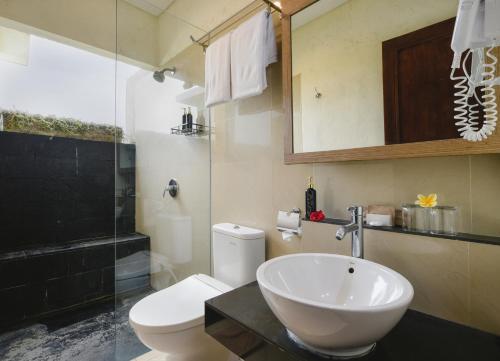 a bathroom with a white sink and a toilet at Bali Breezz Hotel in Jimbaran